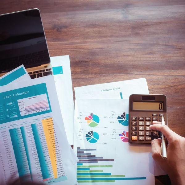 paperwork with graphs and someone using a calculator