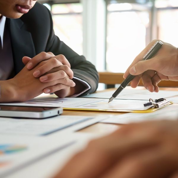 pointing with pen, discussing paperwork on desk