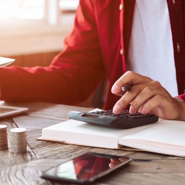 using calculator, stacks of coins and logbook on desk