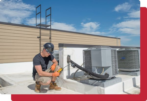 An HVAC tech using a meter on a unit on top of a roof