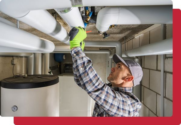 An HVAC tech working on some pipes above a water heater