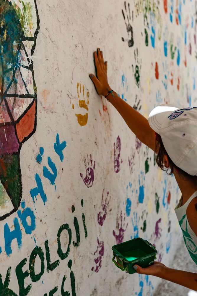 person putting painted hand printed on wall with other hand prints hulki-okan-tabak-3VWrpp51jqw-unsplash.jpeg