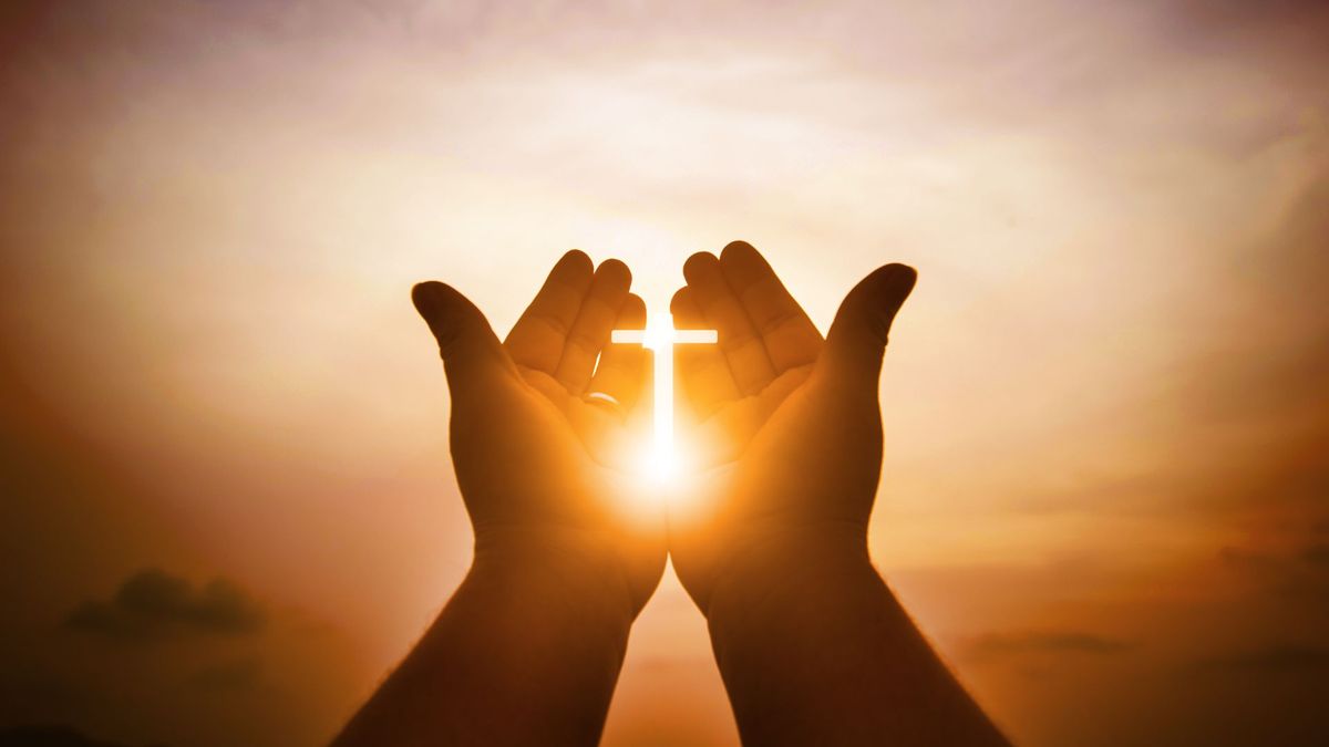 Two hands with a christian cross at the forefront