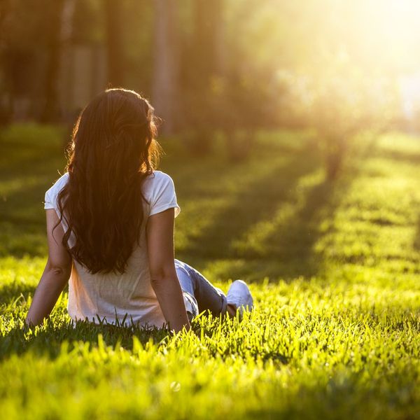 woman sitting on grass and reflecting