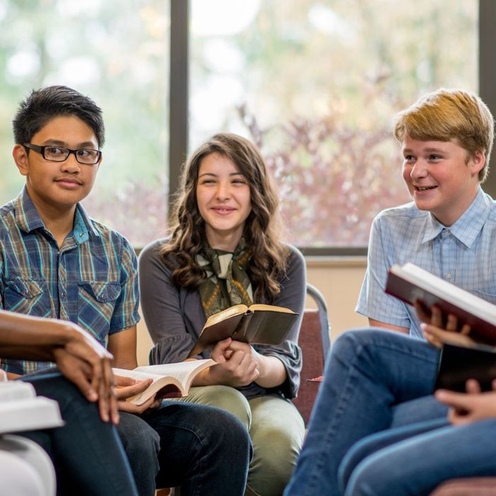 Group of young people reading Bibles, smiling. 