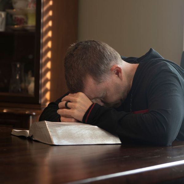 man praying while reading the bible man praying while reading the bible