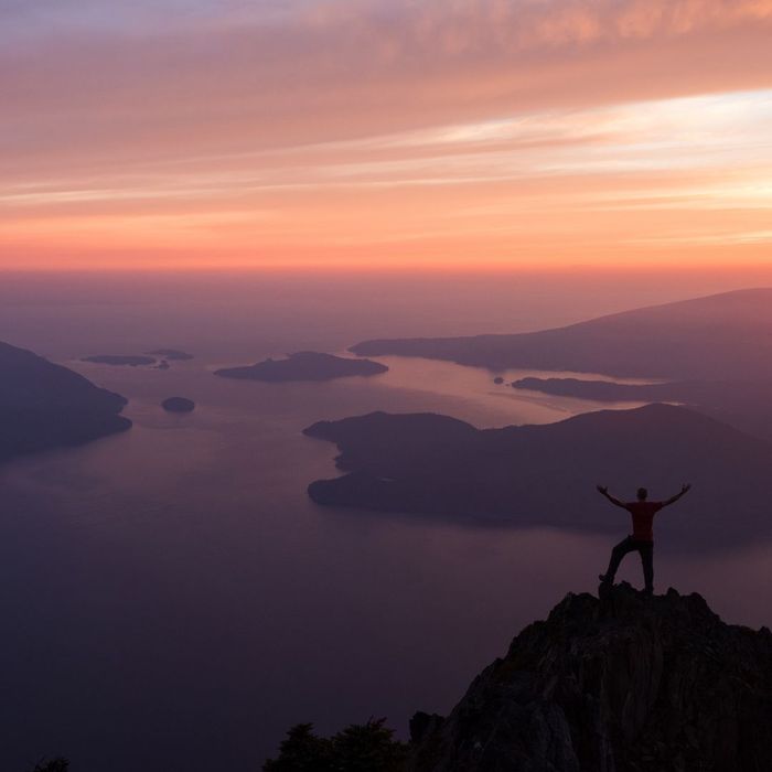 man standing on mountaintop at sunset
