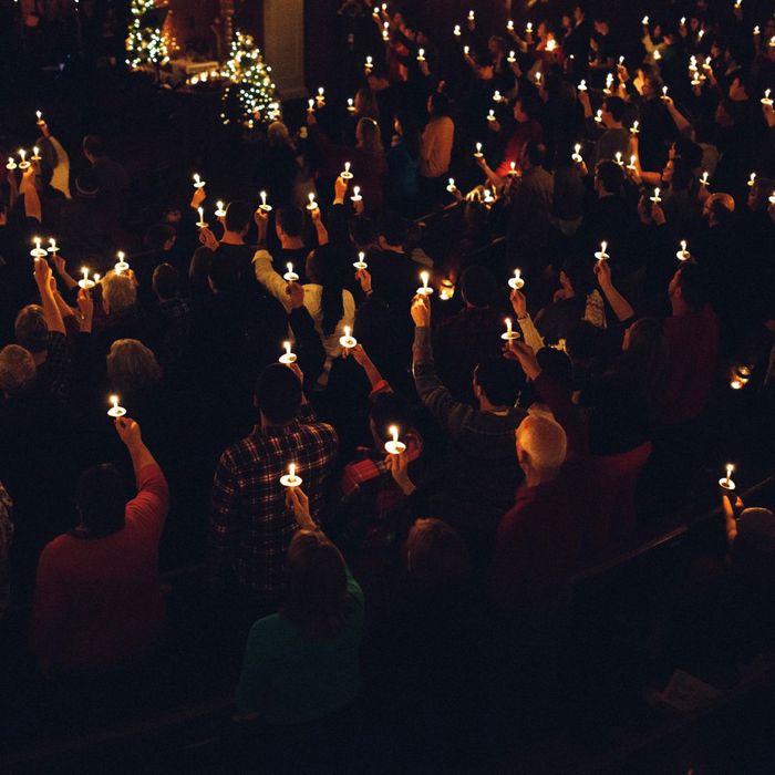 People holding up candles at a church service