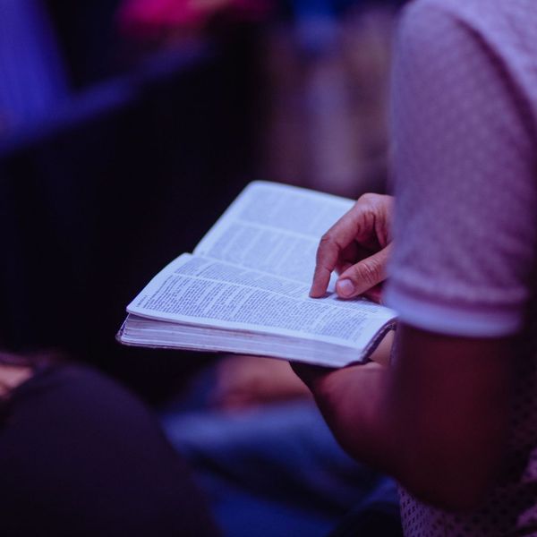 man trailing his finger along the line of a bible passage man trailing his finger along the line of a bible passage