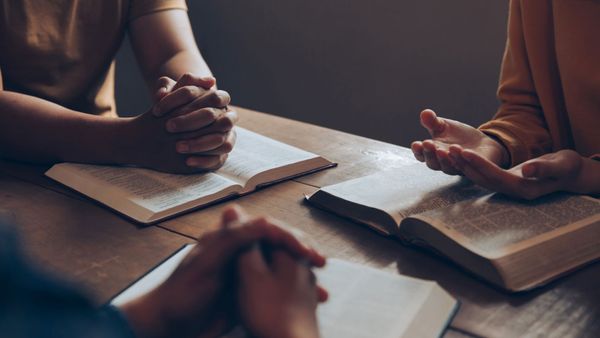 Three people sitting in a circle with Bibles in front of them. 