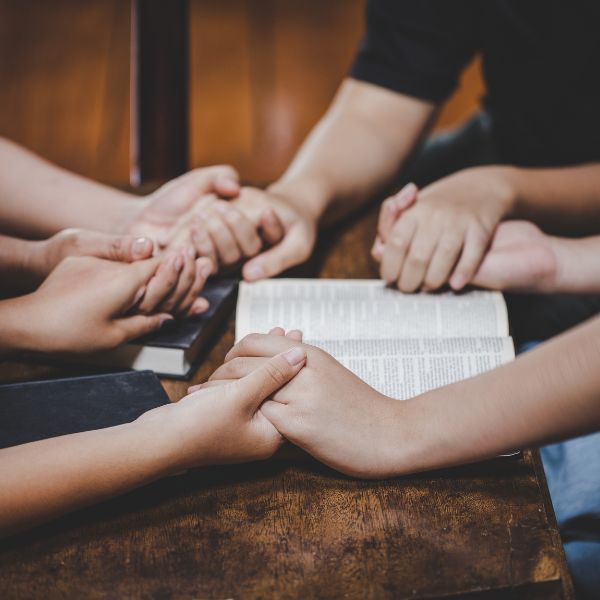 Group holding hands praying