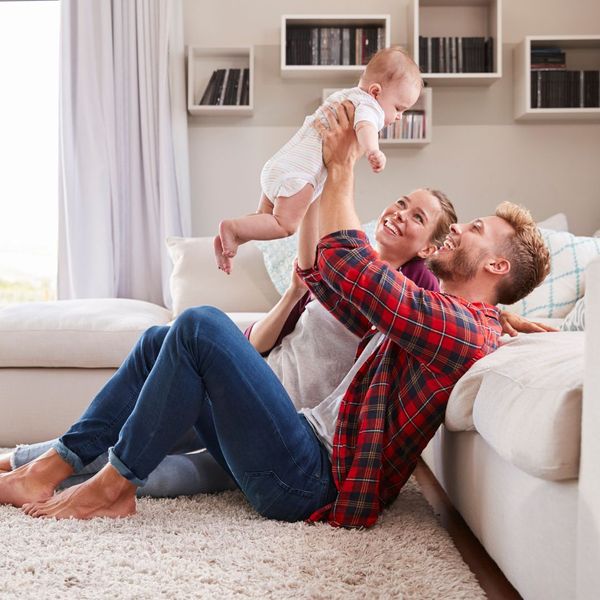 husband and wife holding baby in living room