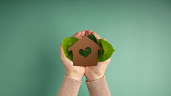 Hands holding brown house and leaves 