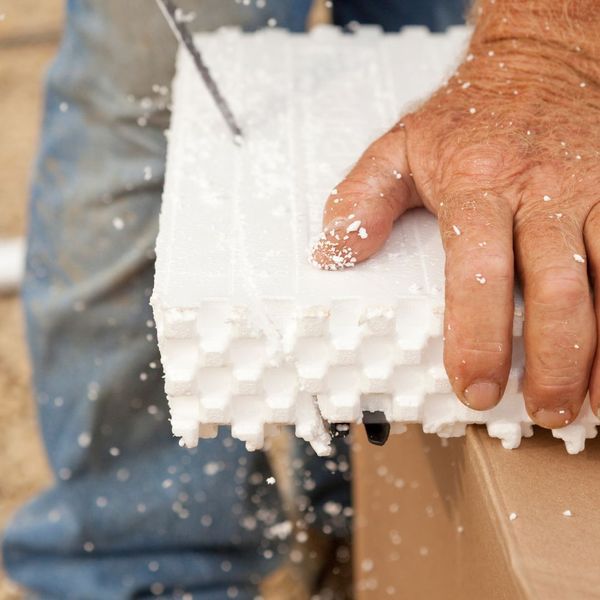 someone sclicing a piece of foam concrete form