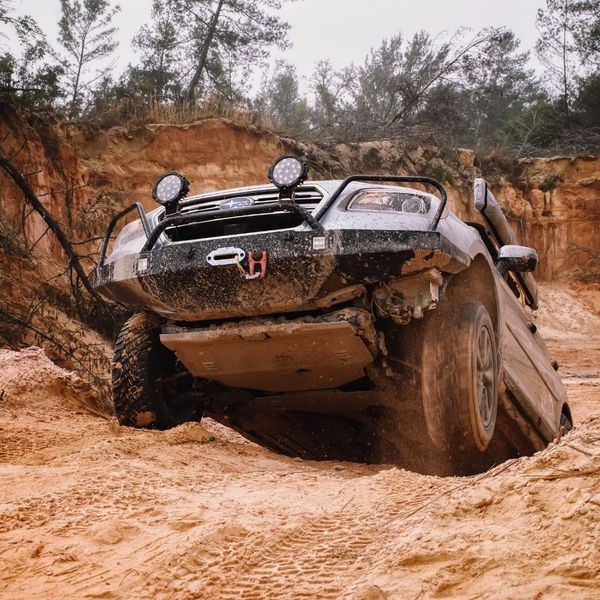 car offroading up a large dirt hill