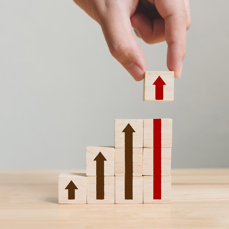 person stacks blocks with arrows that increase in height