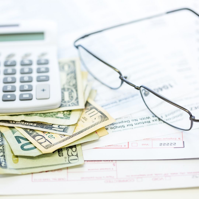 money, calculator, and glasses sitting on a table