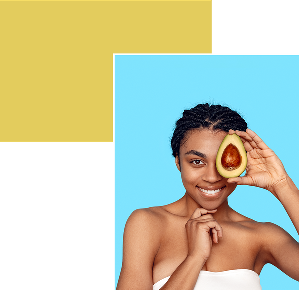 Woman holding avocado up to her face and smiling