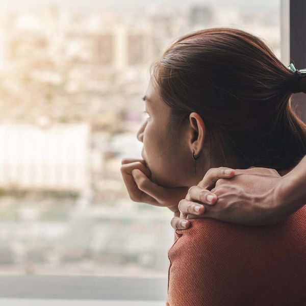 Woman looking sad and someone’s hand on her shoulder. 