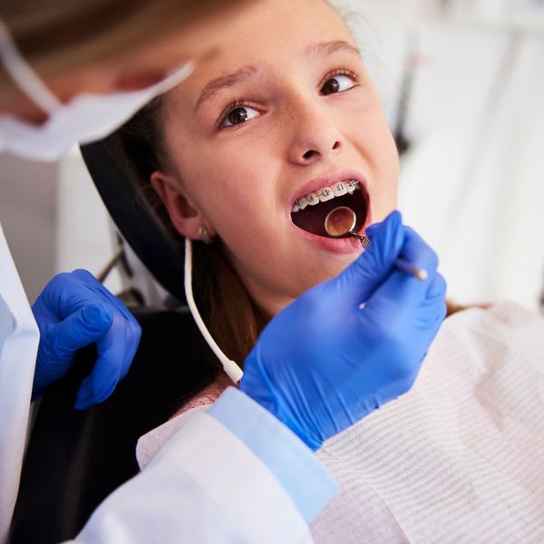 girl with braces with a dentist checking her teeth