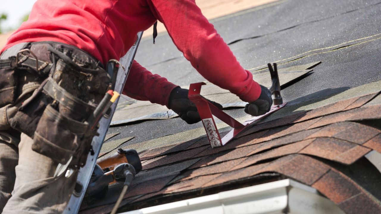 Roofer installing shingles on roof