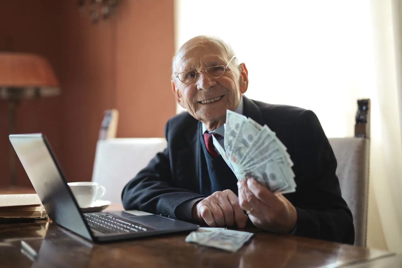 An older business owner holding a stack of money