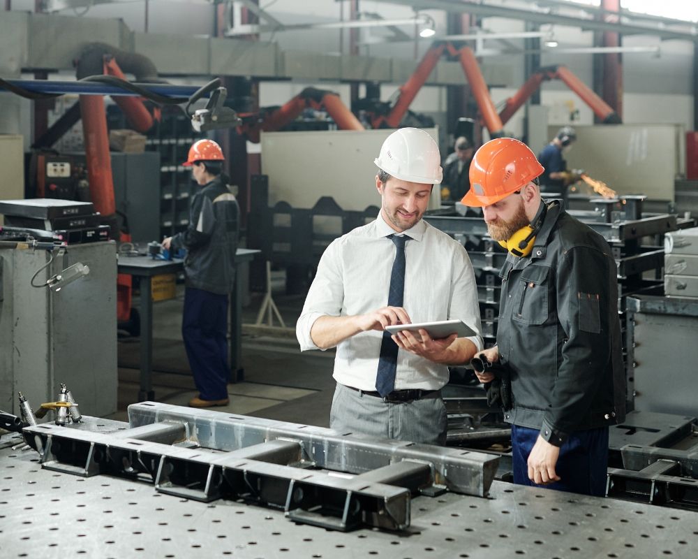 Two engineers in hardhats at a manufacturing plant