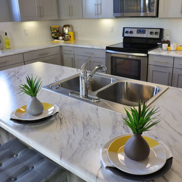 A kitchen island with a double sink is shown, topped with a white and gray marbled countertop. island.jpg