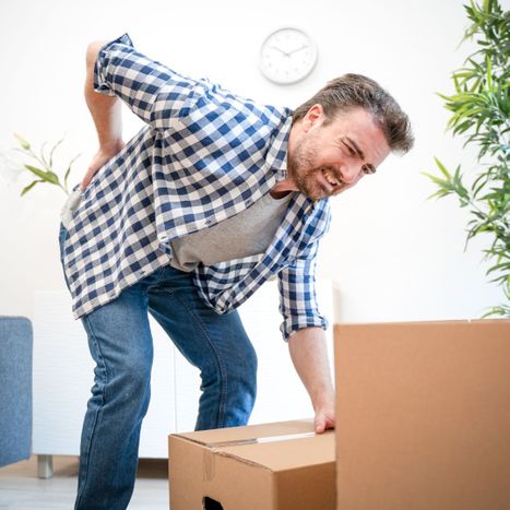 man holding his back as he lifts a box