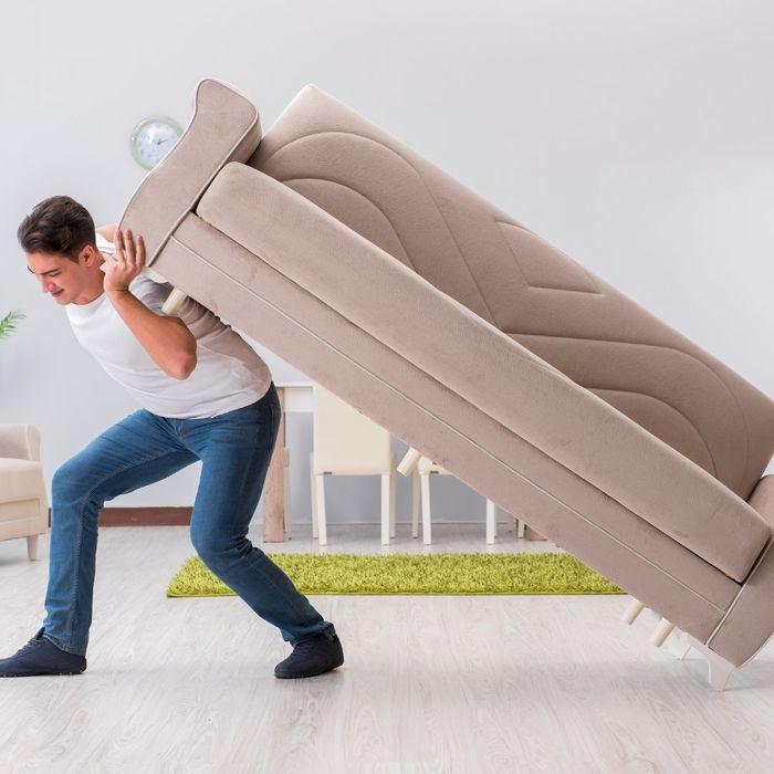 Man trying to move a couch alone