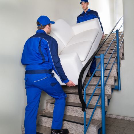 Professional movers carrying a couch down stairs