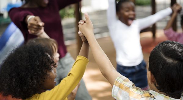 children sitting in a circle holding hands. 