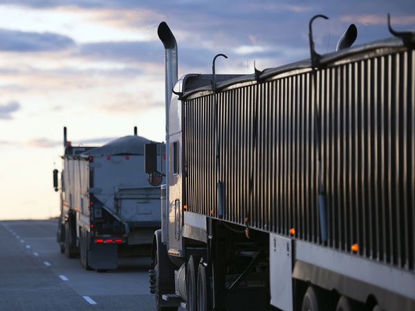 A view of two trucks driving on a highway.