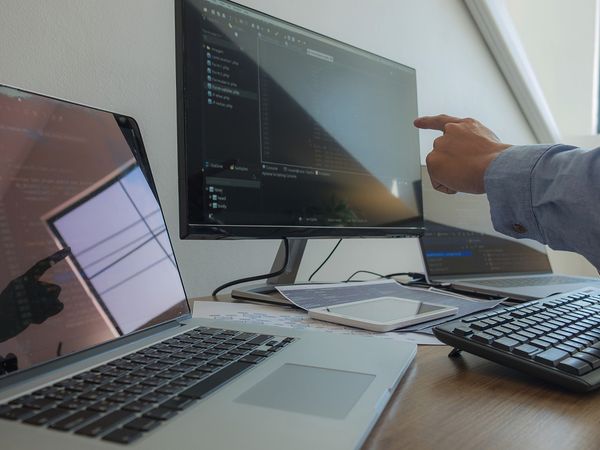 An image of a man pointing to a computer screen.