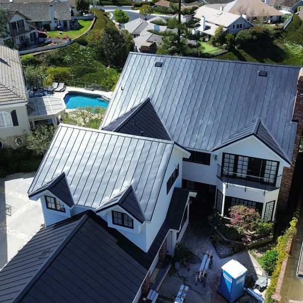 The sun glints off the clean, vertical lines of a newly installed standing seam metal roof.