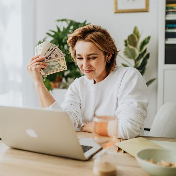 smiling woman holding cash while looking at lowered bills smiling woman holding cash while looking at lowered bills