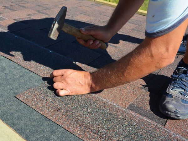 An image of someone fixing shingles on a roof.