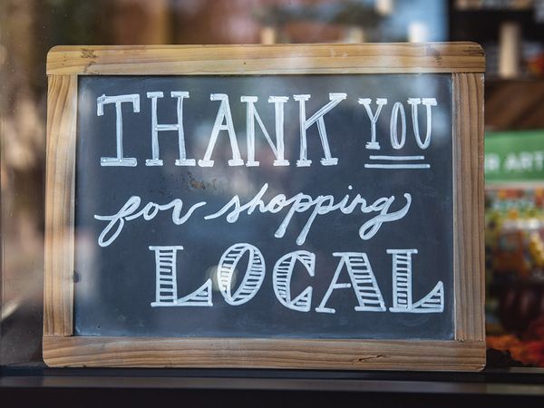 Sign that reads Thank You For Shopping Local in different fonts on a chalkboard