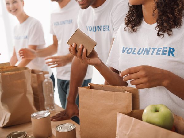 People wearing volunteer shirts putting donated food into paper bags