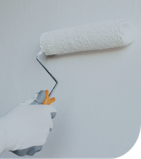 a hand holding a roller brush painting a wall
