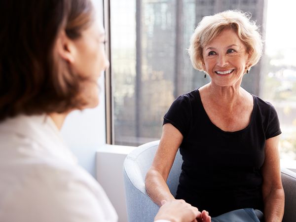 Senior woman smiling while talking to younger adult