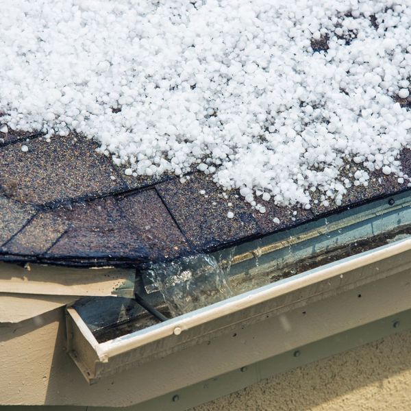 Close-up of a roof with snow on it showing damaged shingles