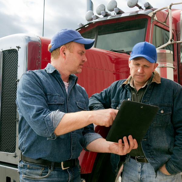 One man training another with a tablet in front of a semi truck One man training another with a tablet in front of a semi truck
