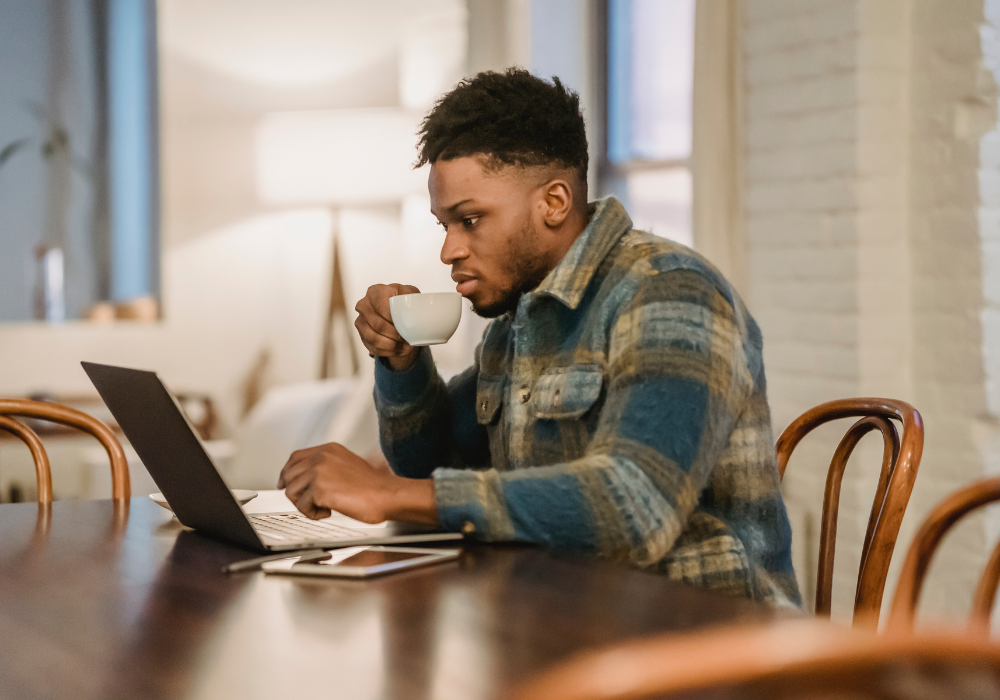 man working on laptop drinking cup of coffee man working on laptop drinking cup of coffee