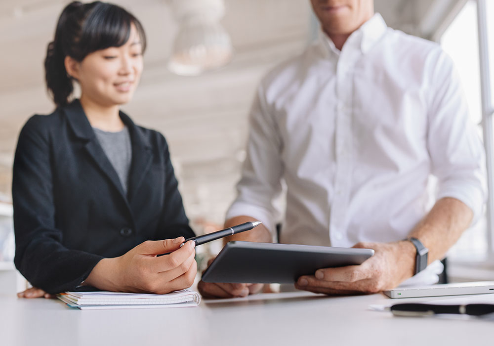 Business woman and man talking and looking at a tablet