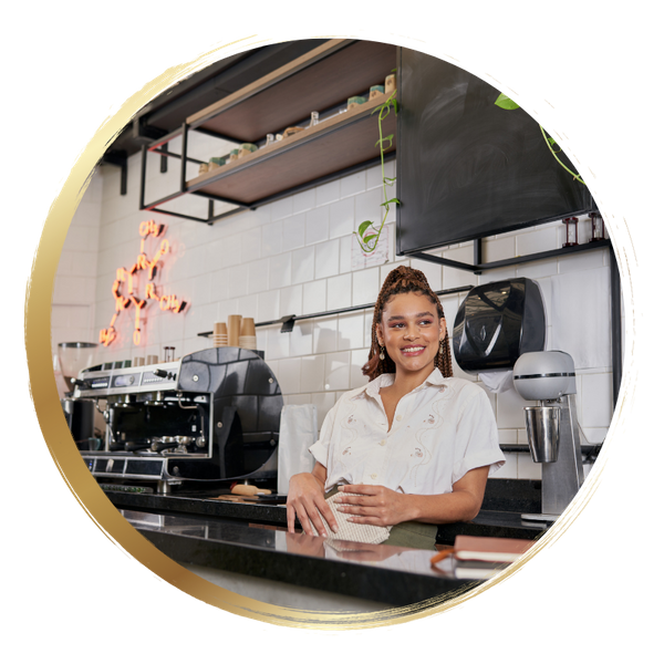 business owner leaning against counter smiling