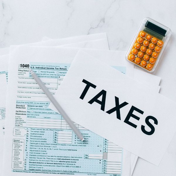 Tax documents spread on a marble table with a pen and calculator.