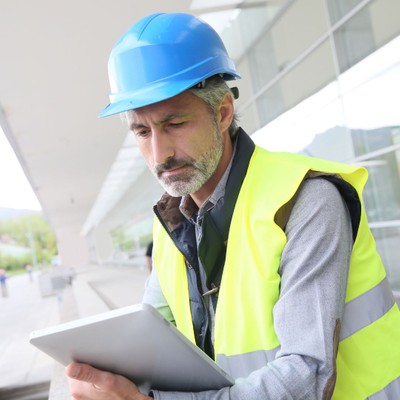 contractor wearing hard hat looking at tablet