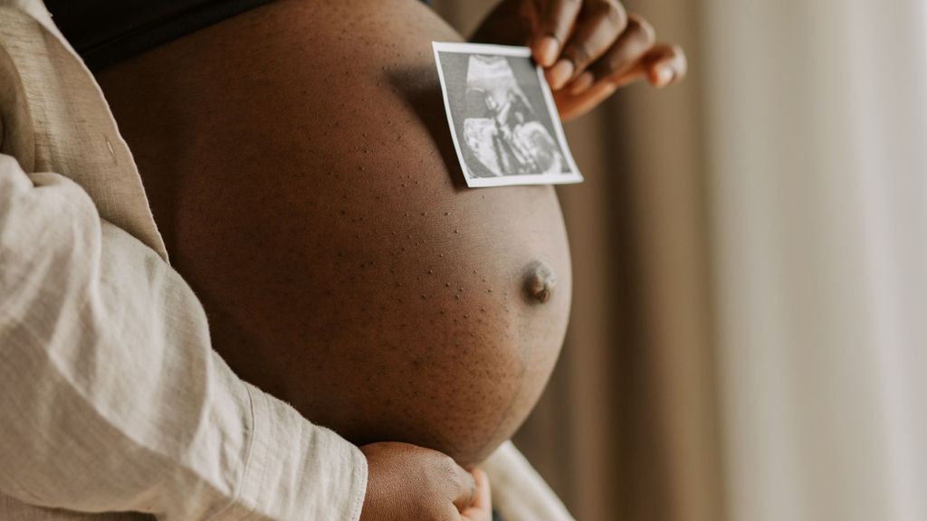 pregnant woman holding ultrasound to belly