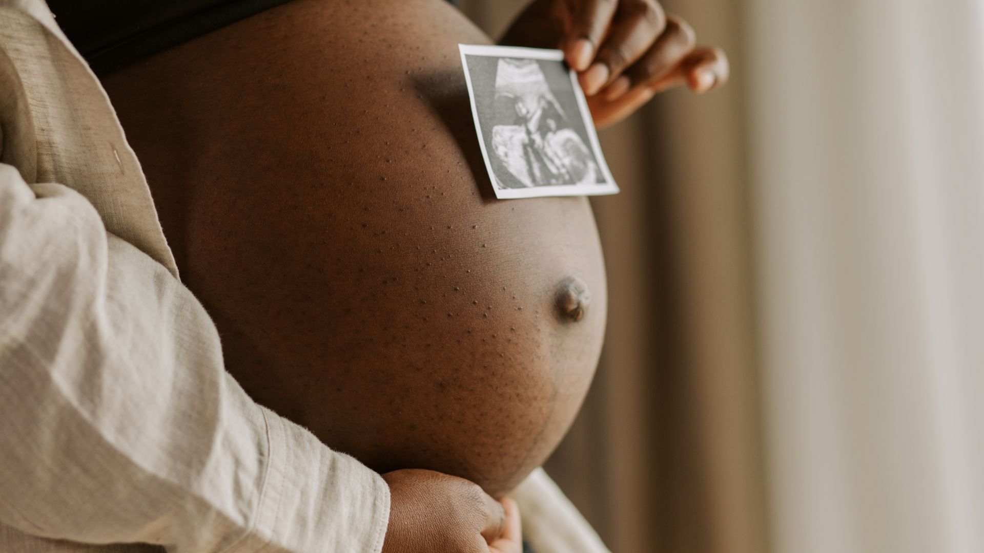 pregnant woman holding ultrasound to belly